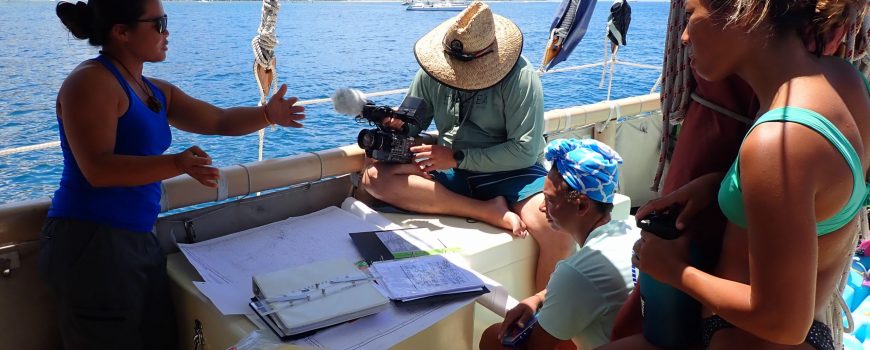 Navigator Tamiko explains the nav plan while crew listen on.